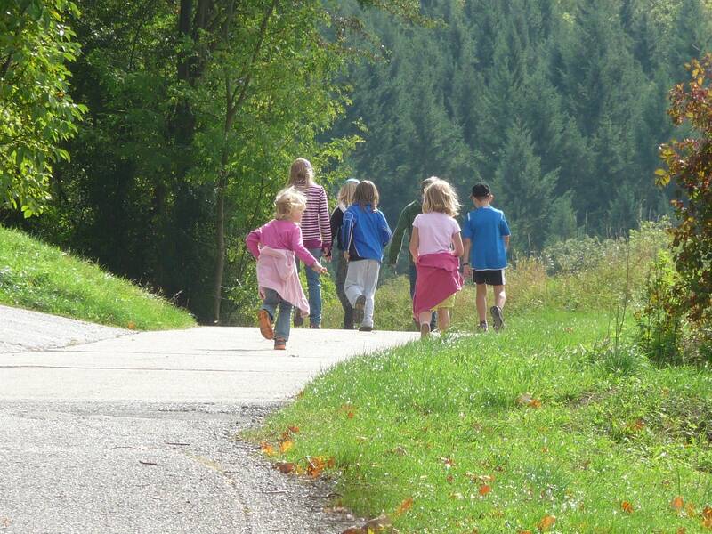 Kinder laufen auf einer STraße im Wald