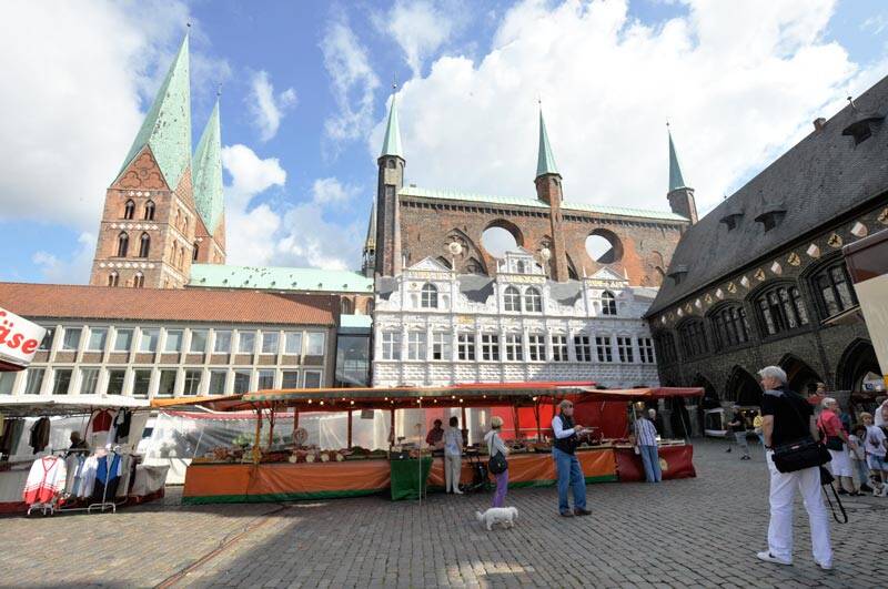 Dorfplatz mit einem aufgebautem Markt und einer Kirche im Hintergrund.